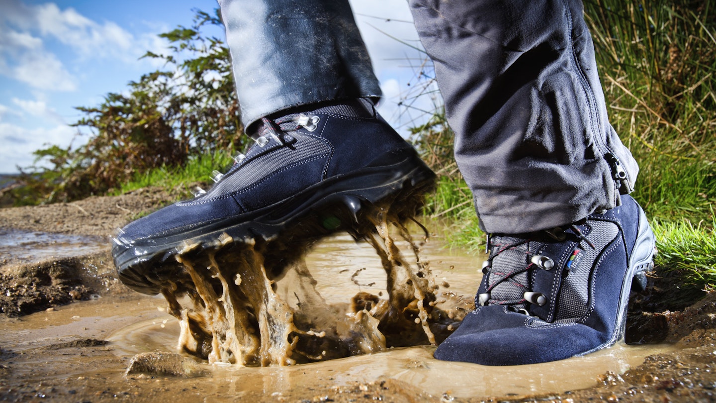 Hiking footwear splashing through a mud puddle