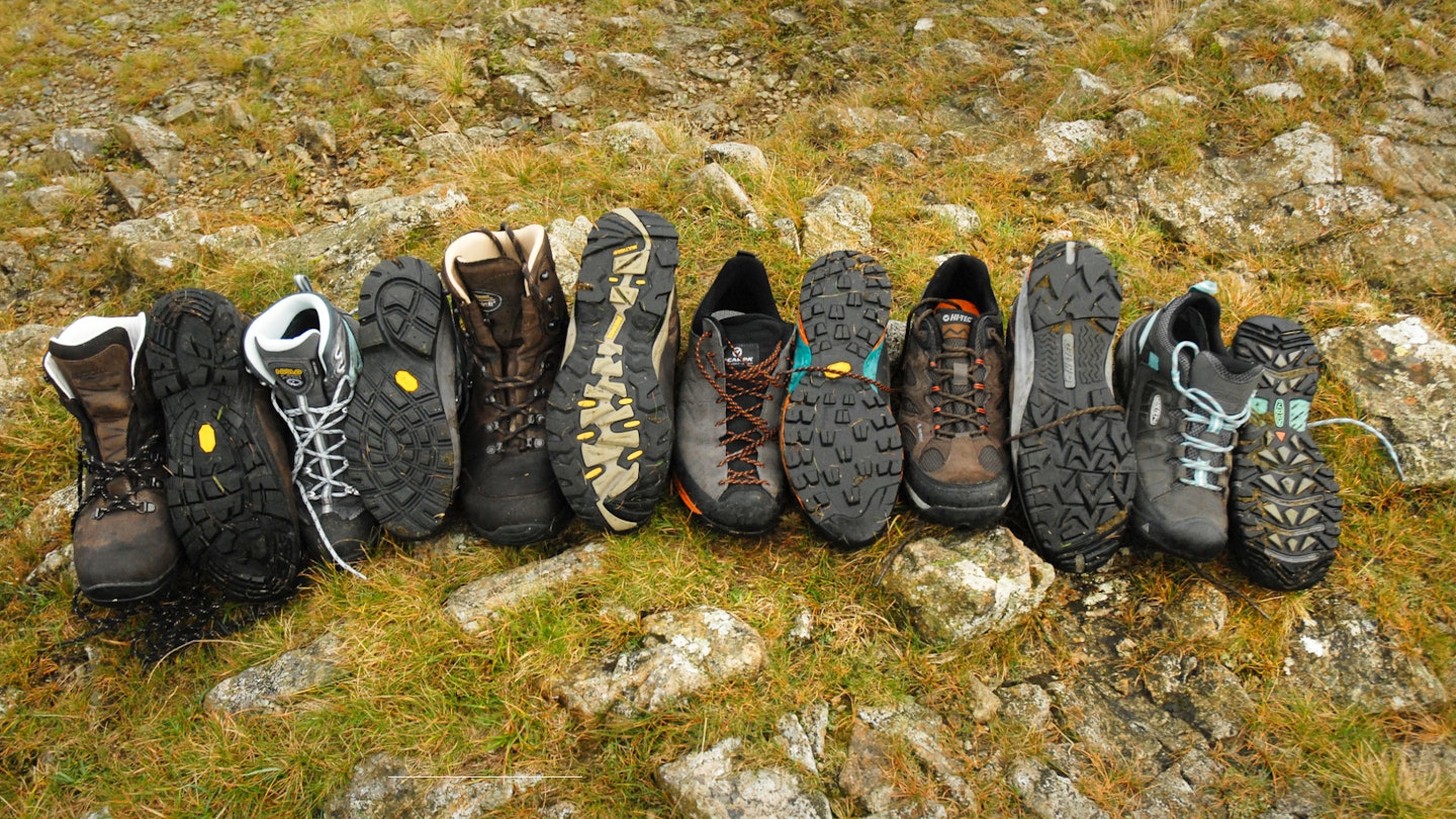 A range of hiking footwear lined up on the grass