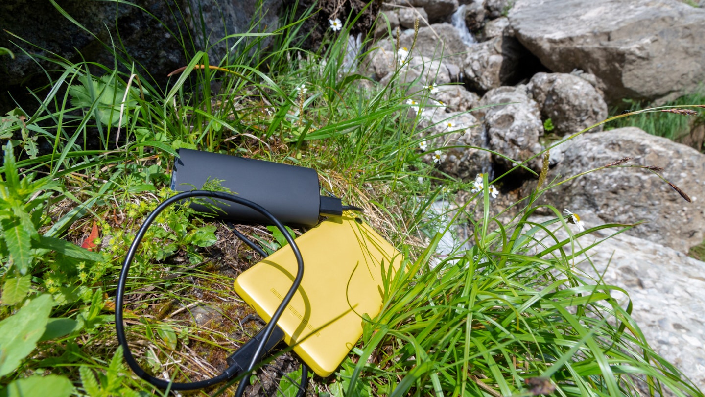 Power bank and smartphone sitting among grass and rocks