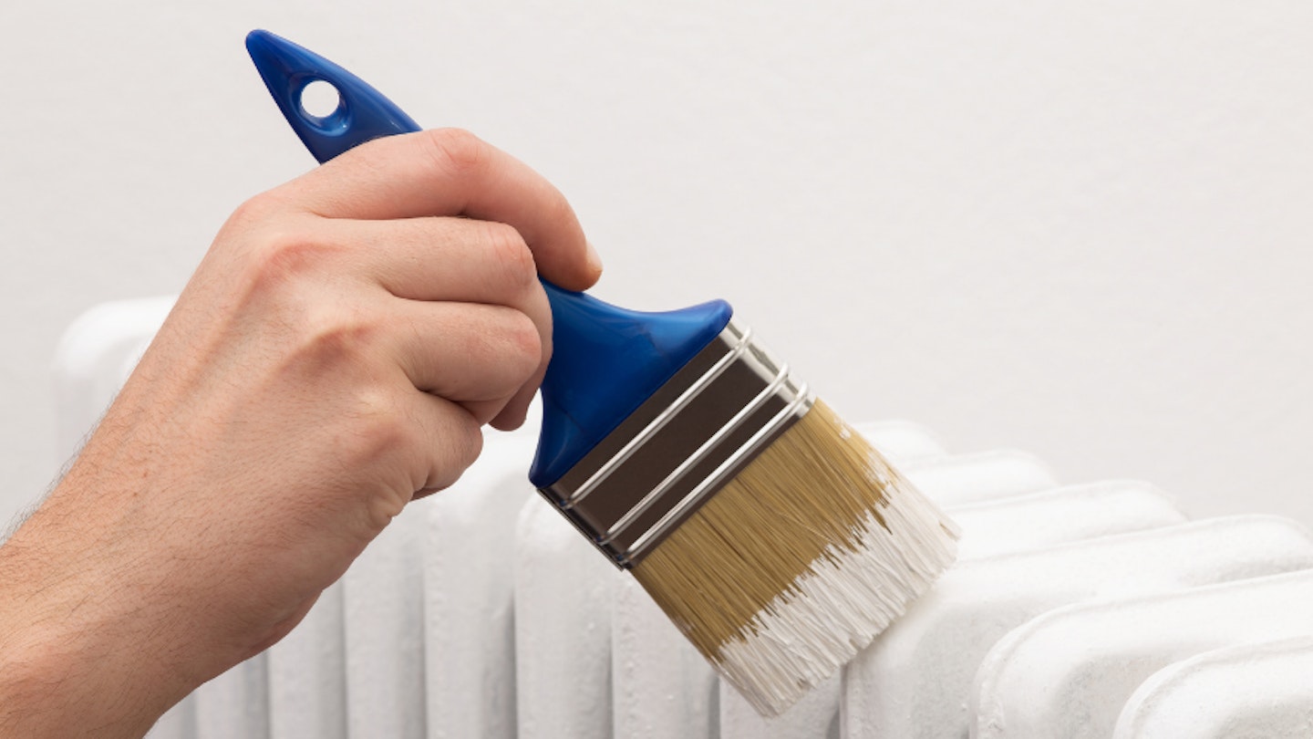 A person painting a radiator white