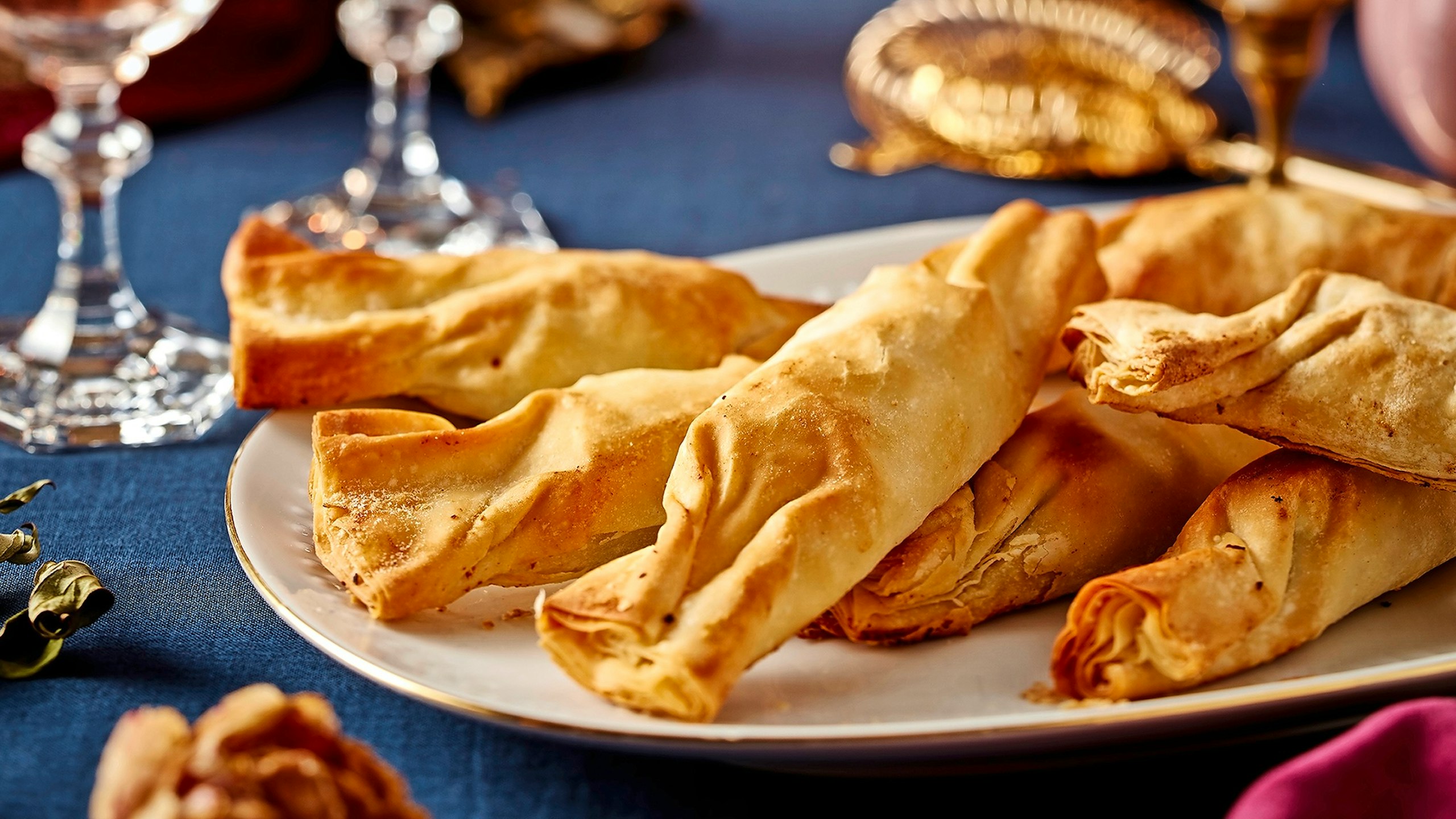 Mincemeat and cheese twists on a table decorated with a blue tablecloth and glasses for a New Year's meal