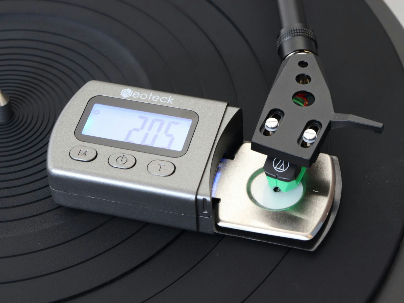 a turntable tonearm and headshell being weighed on digital scales