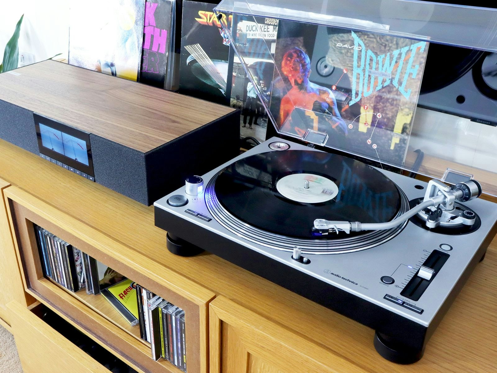 An Audio-Technica AT-LP140 budget record player on a unit with an amp and LPs