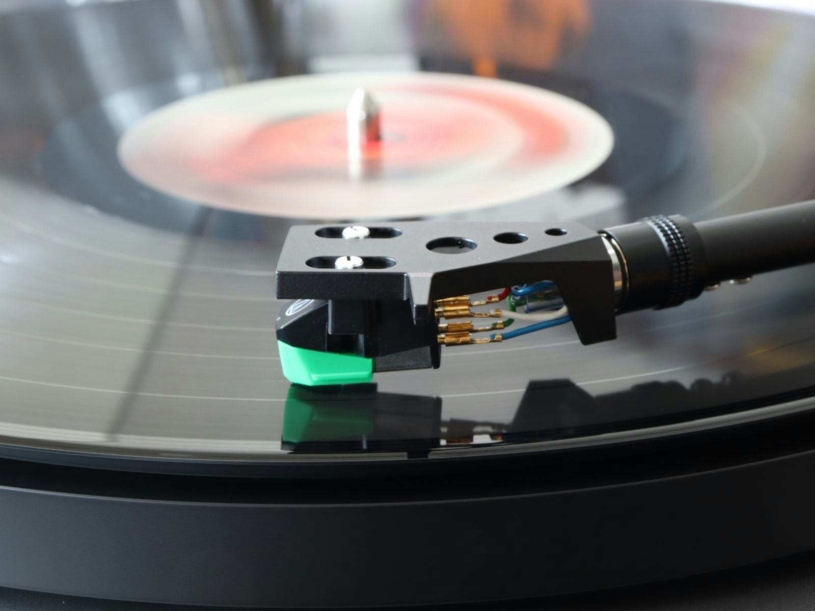 A record player headshell and stylus playing a record