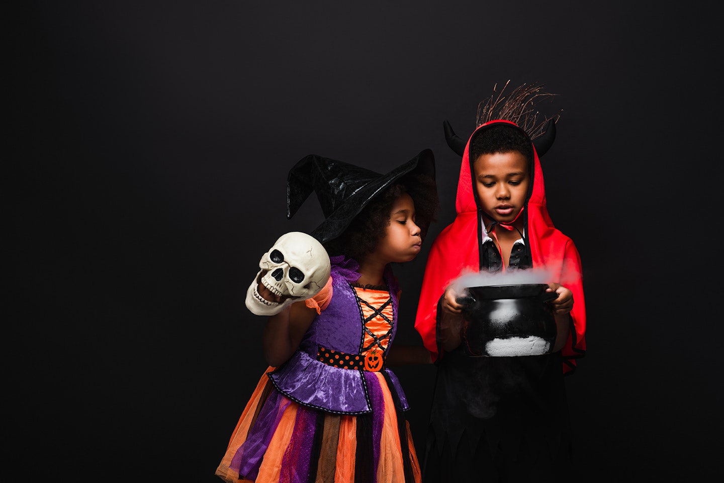 Boy and girl dressed as witches with cauldron