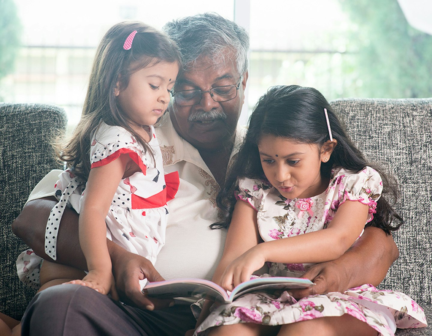 Grandfather and granddaughters reading