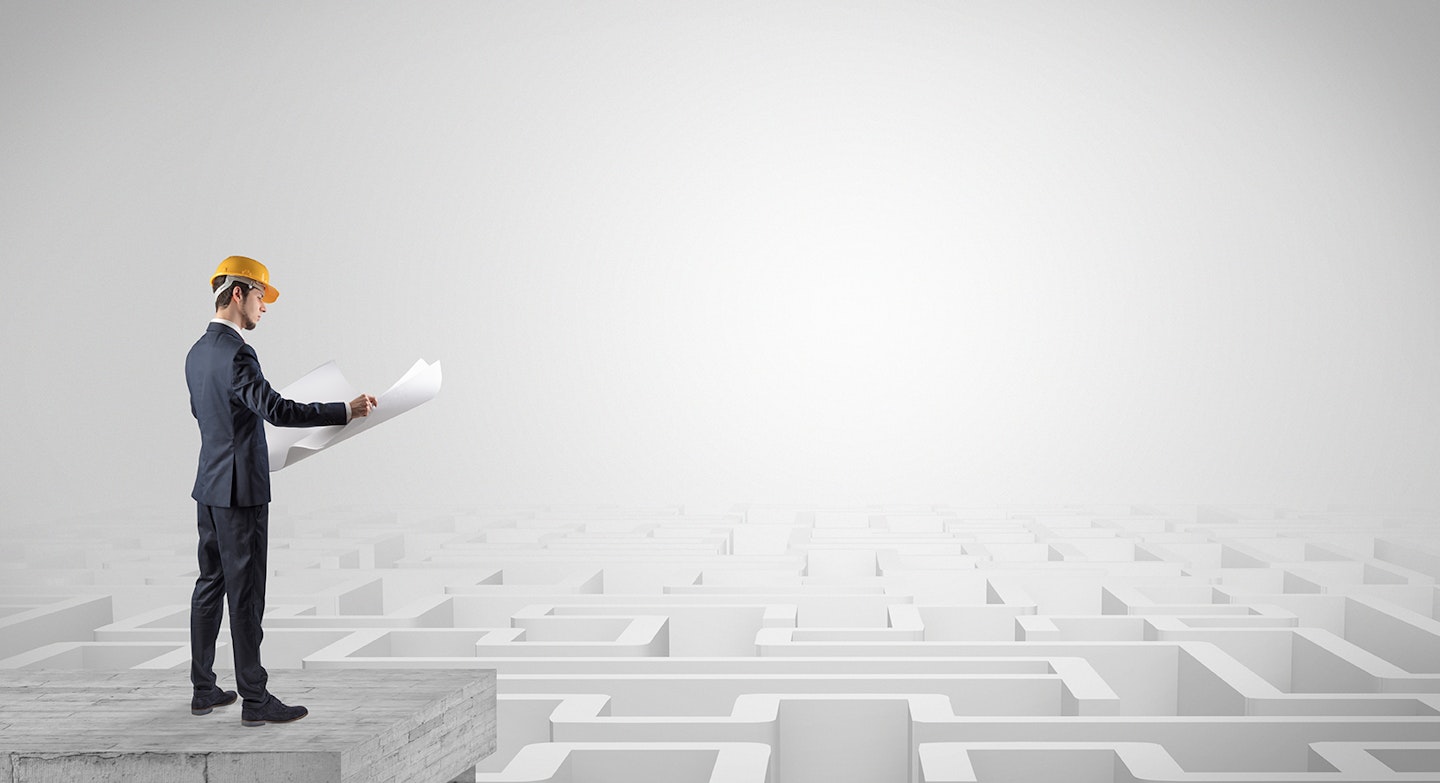 Architect standing on maze and looking at a future plan