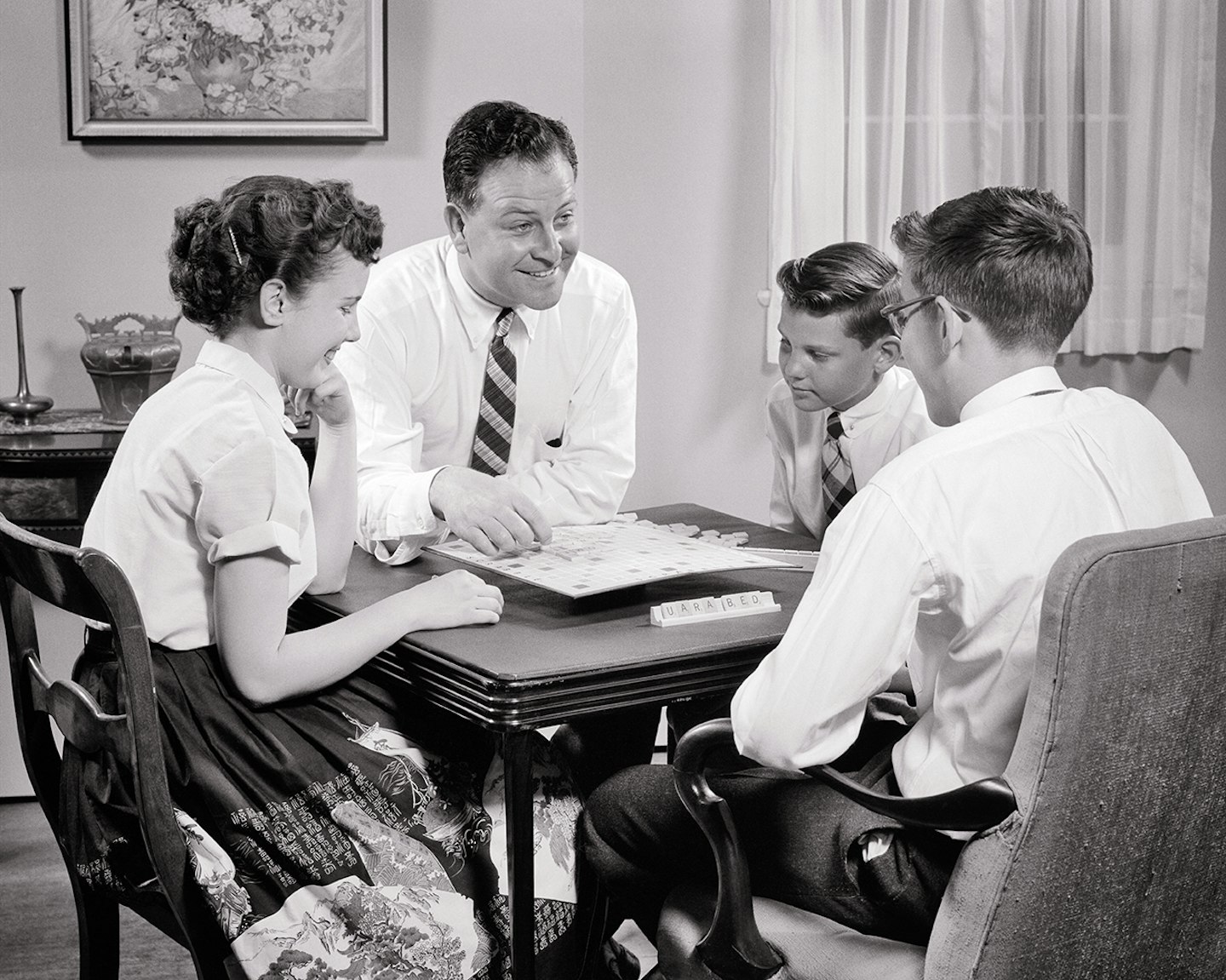 1950s Father Playing Game Of Scrabble With His Three Teenage Kids A Girl And Two Boys Sitting At Living Room Folding Card Table (Photo by H. Armstrong Roberts/ClassicStock/Getty Images)