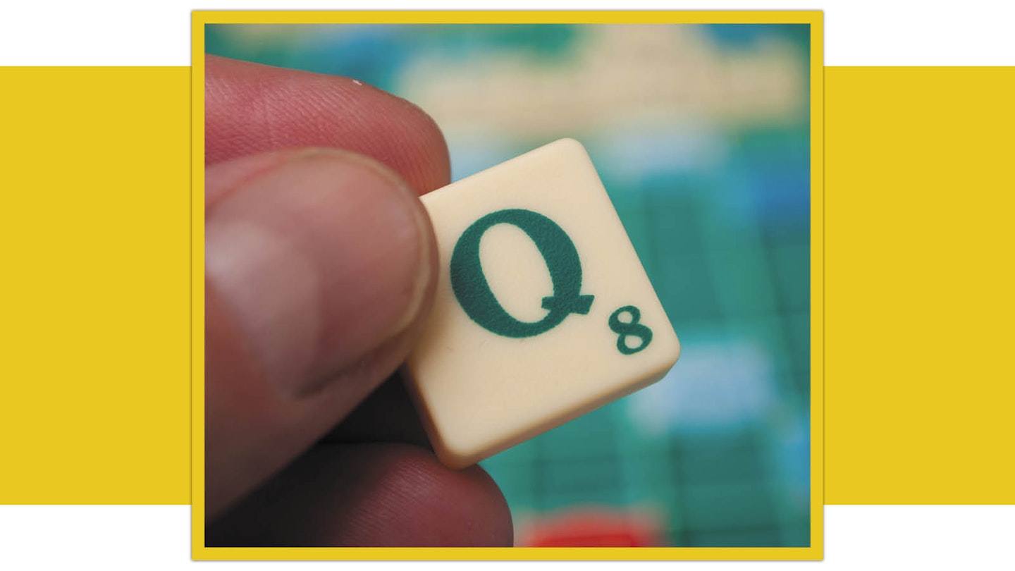 Scrabble tile letter Q being held over board
