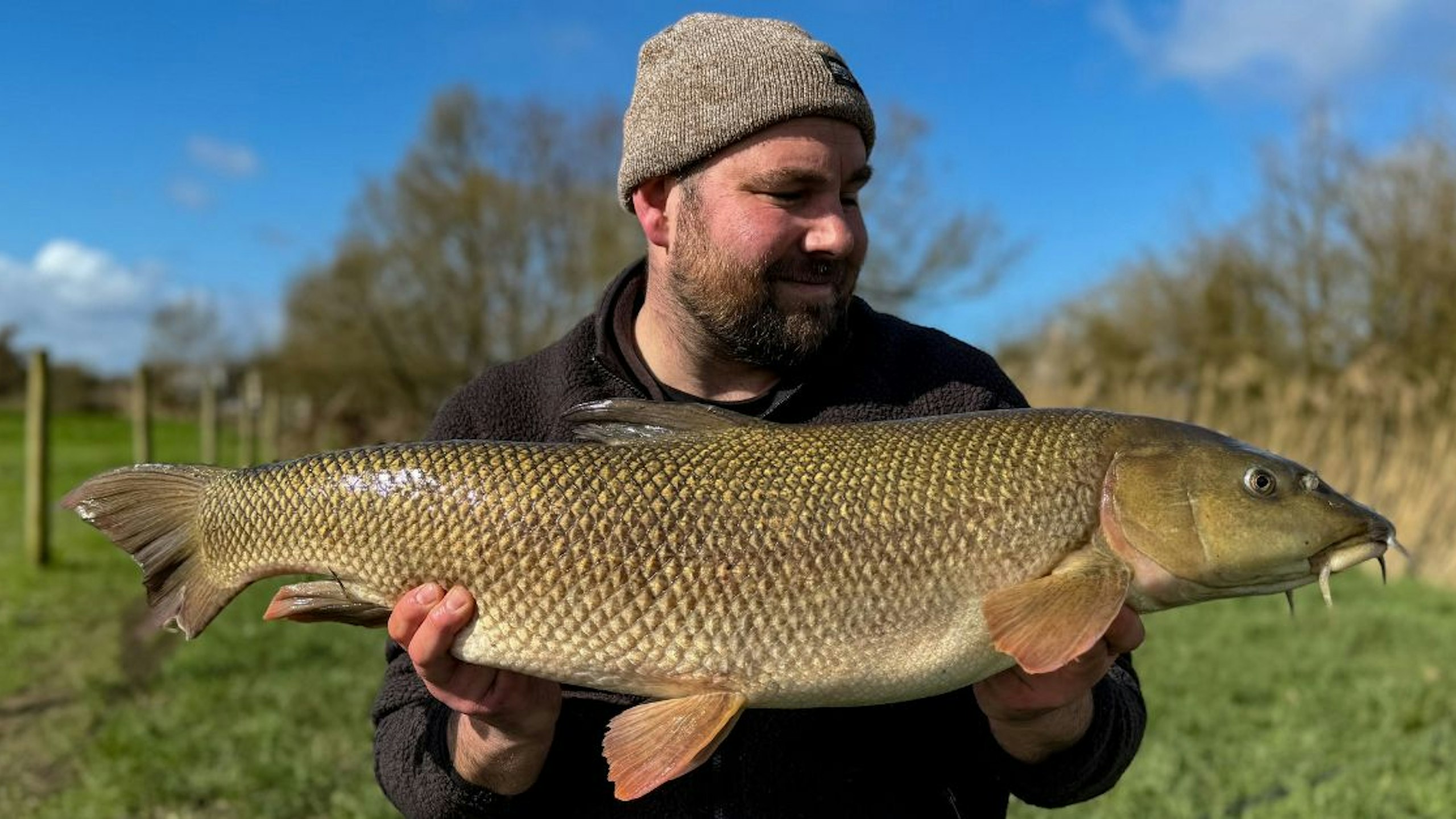 Angler holding a stunning barbel caught during the coarse fishing season