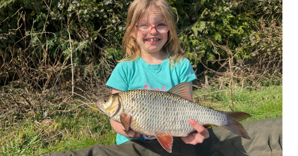 young female angler holding huge roach