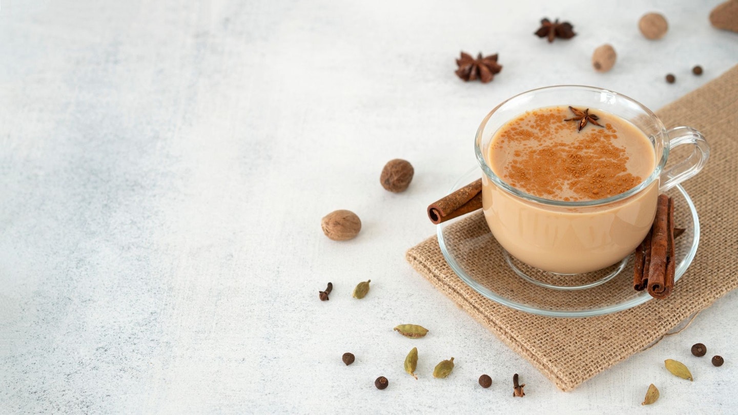 Traditional Indian Masala Tea In A Glass Cup With Cinnamon, Ginger, Cardamom, Anise, Honey, Milk