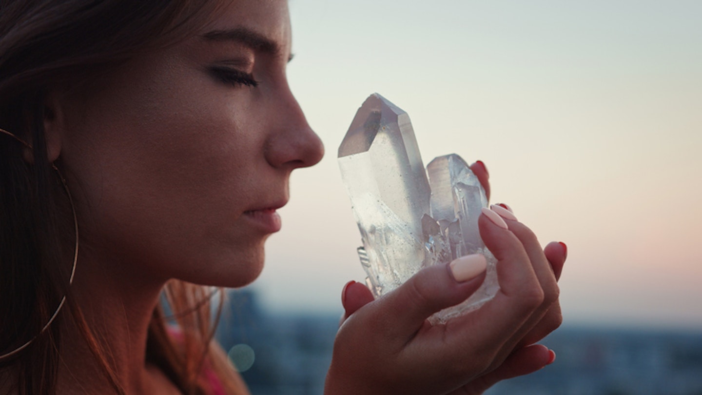 Crystal healing. Woman on a rooftop with city panorama. Magical meditation