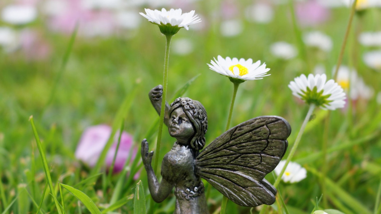 Romantic fairy garden ornament, holding a daisy in the garden.