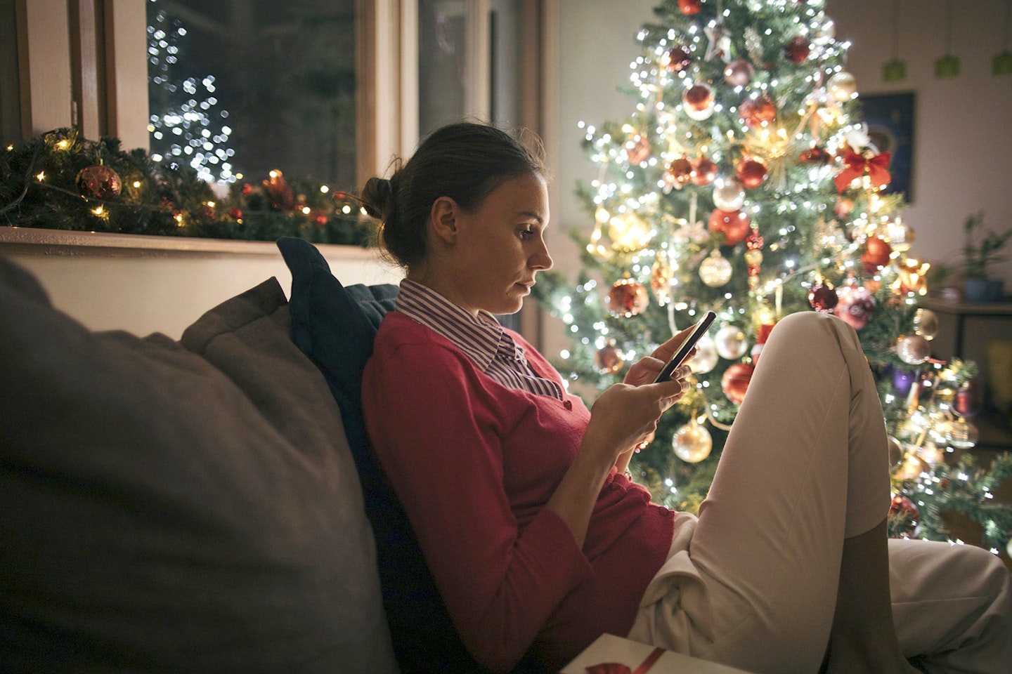 woman sat next to decorated Christmas tree