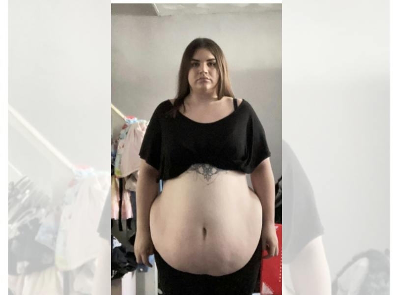 Woman with dark hair with her belly out