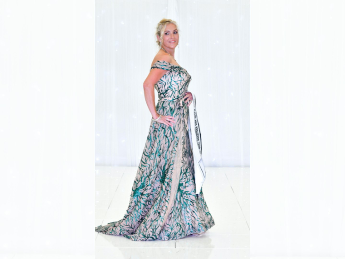 Blonde woman in long dress holding beauty pageant sash
