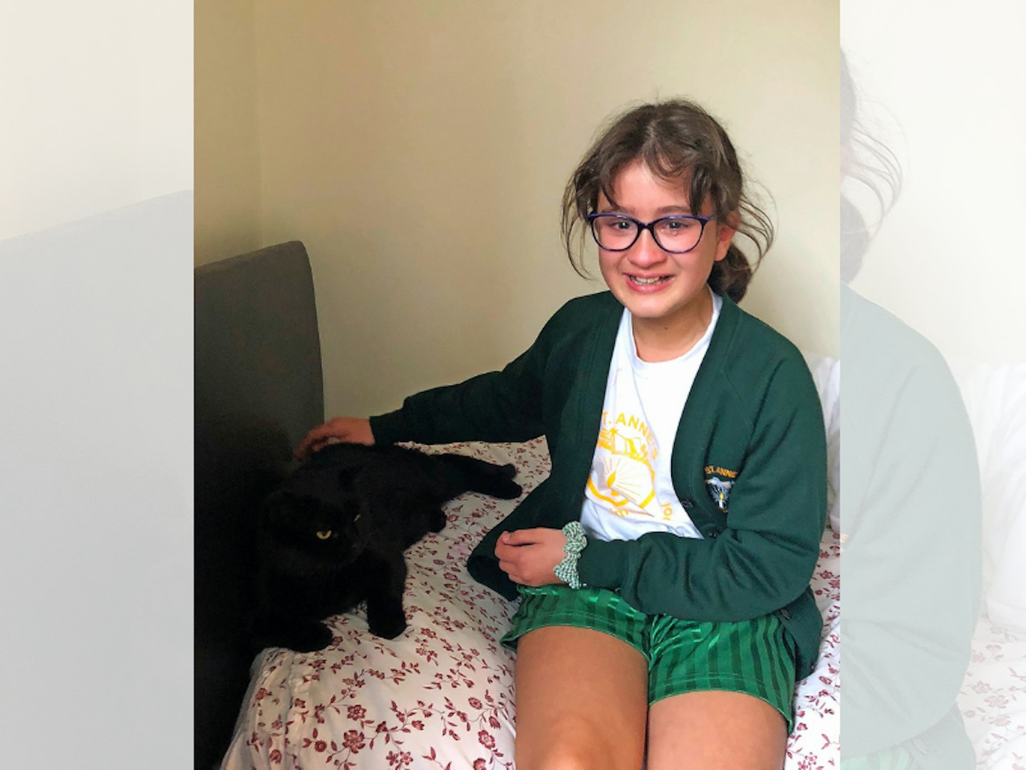 girl in school uniform sitting on a bed with a black cat