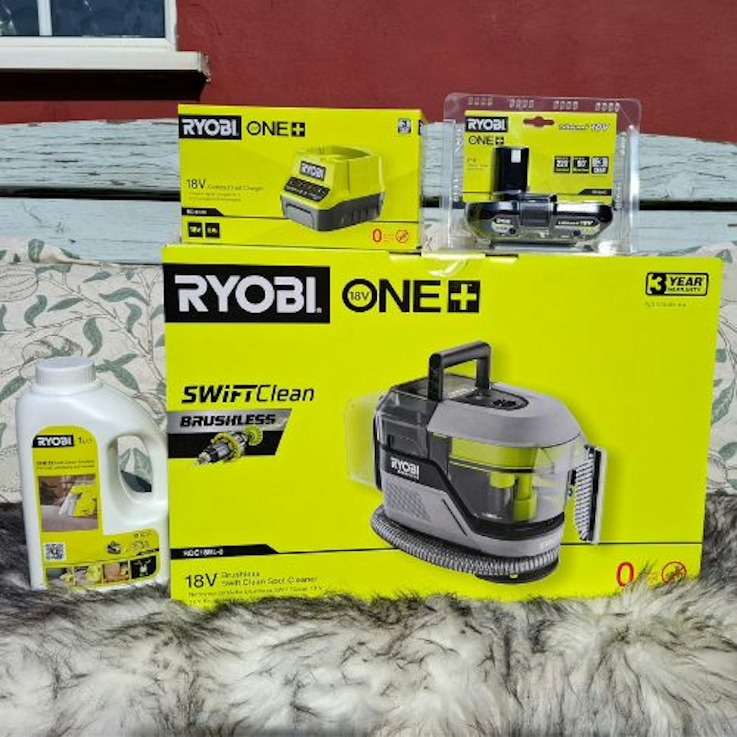 photo of the Ryobi 18V ONE+™ Cordless Brushless Swift Clean Stain Remover Starter Kit on a bench in the sun