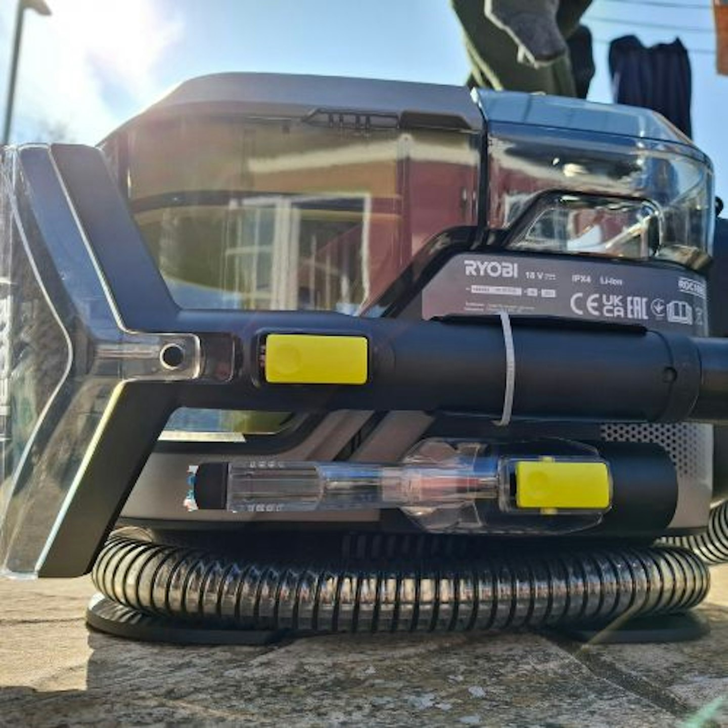 back view of the Ryobi 18V ONE+™ Cordless Brushless Swift Clean Stain Remover in a sunny garden