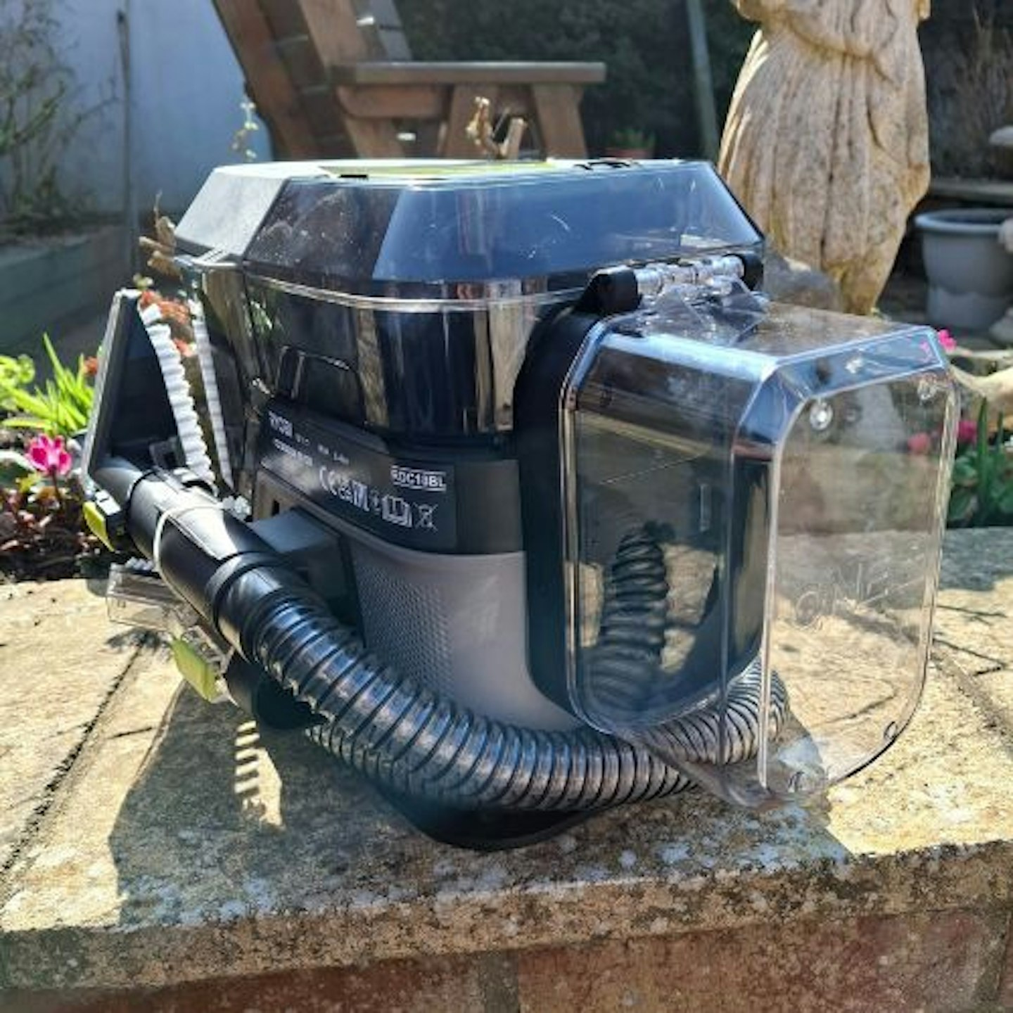Ryobi 18V ONE+™ Cordless Brushless Swift Clean Stain Remover side view in a sunny garden