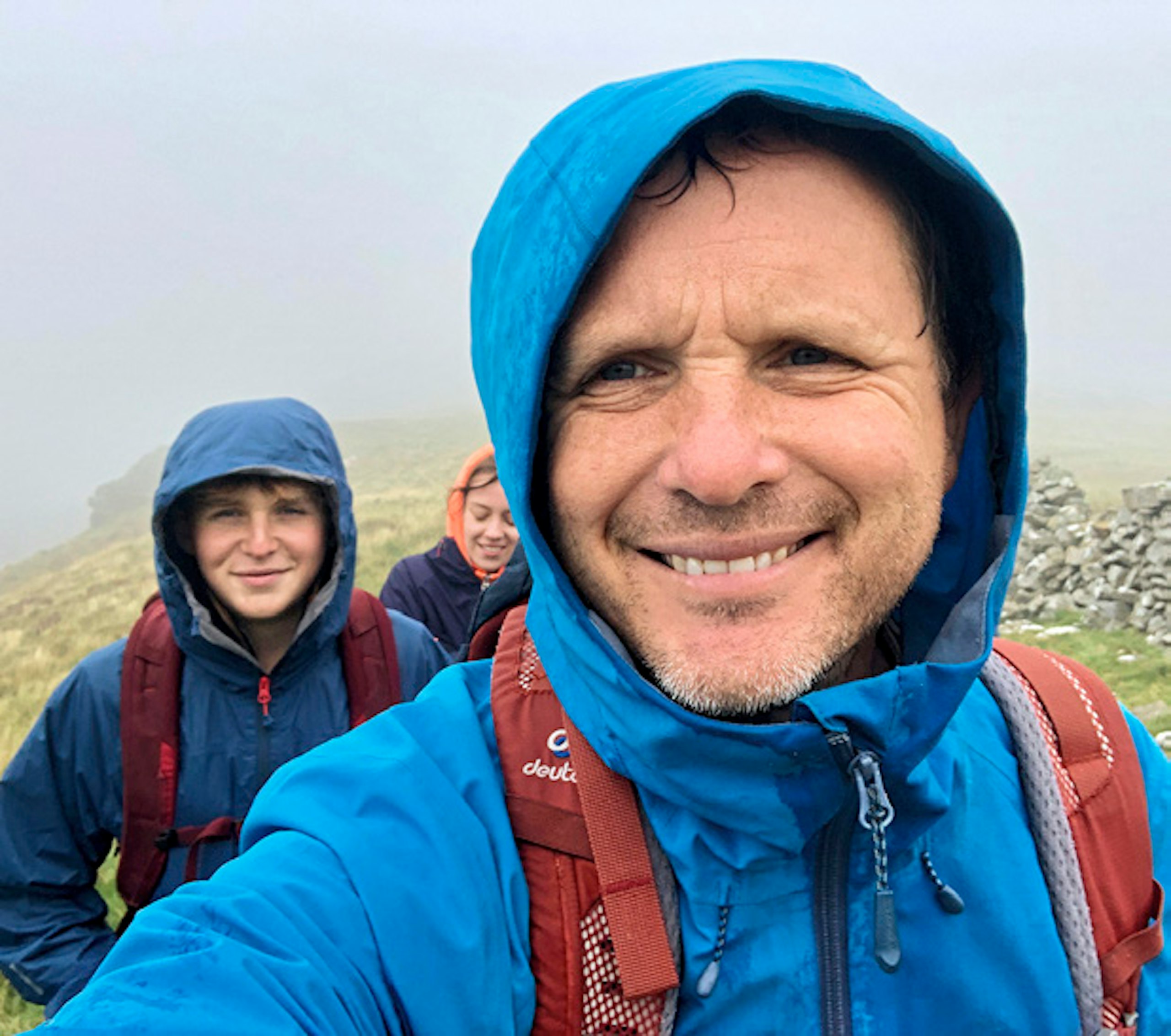 Guy and family smiling during a wet and windy walk